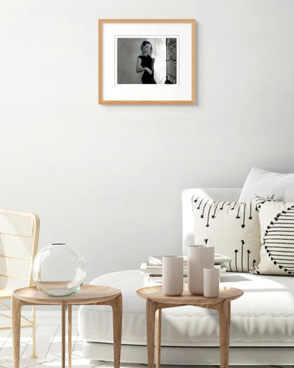 Framed Kylie Minogue portrait by Robin Sellick displayed above a white couch with soft neutral styling – contemporary Australian interior.