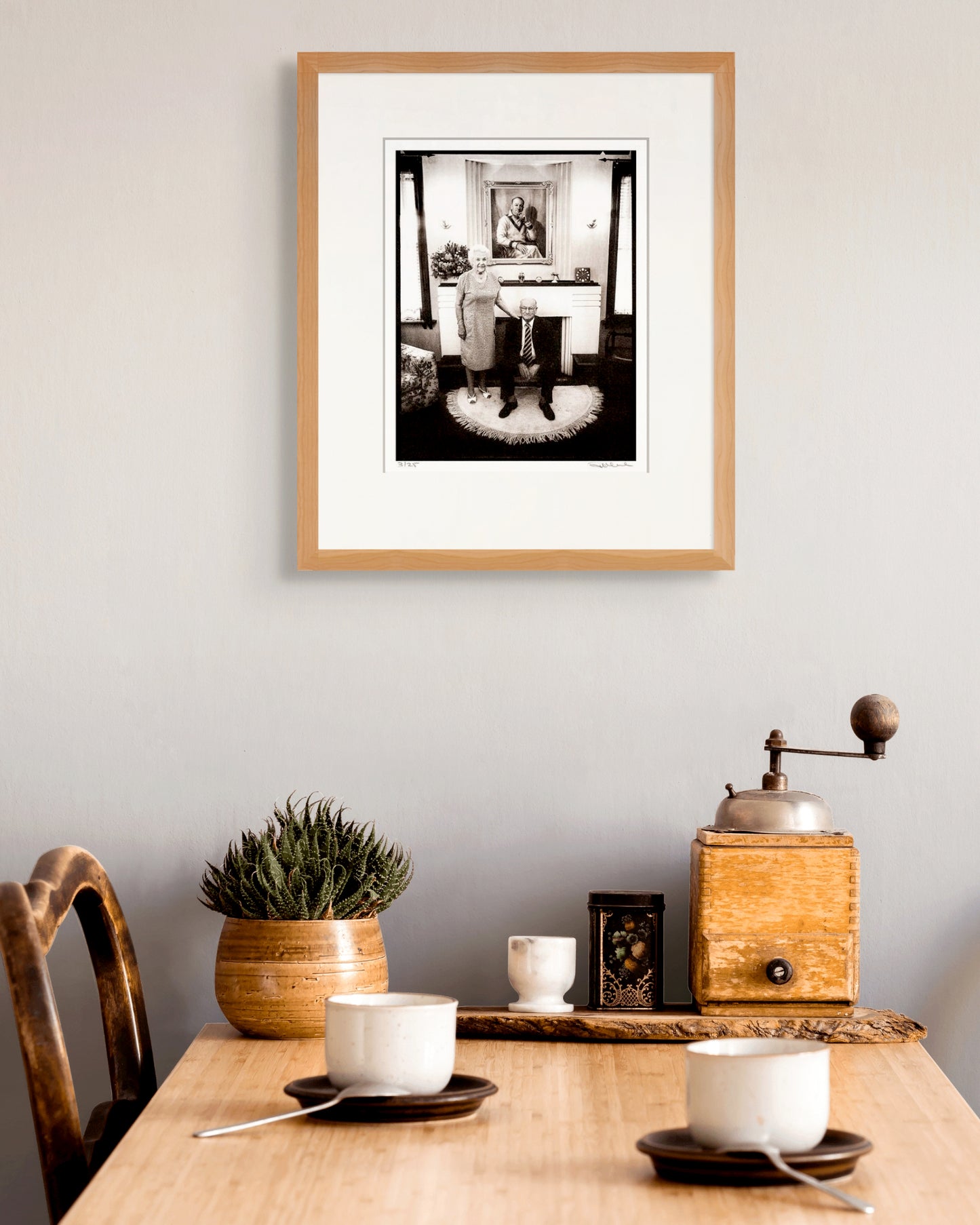 Framed Bradman portrait by Robin Sellick above a breakfast table with vintage coffee cups and succulents – nostalgic and intimate Australian styling.