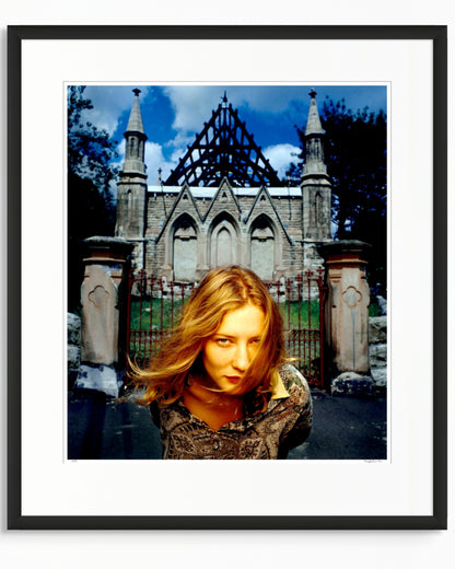 Framed colour photographic portrait of Cate Blanchett photographed in Woollahra, Sydney in 1994, standing before a Gothic stone structure, by Robin Sellick.