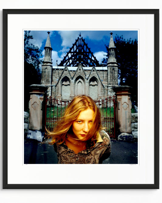 Framed colour photographic portrait of Cate Blanchett photographed in Woollahra, Sydney in 1994, standing before a Gothic stone structure, by Robin Sellick.