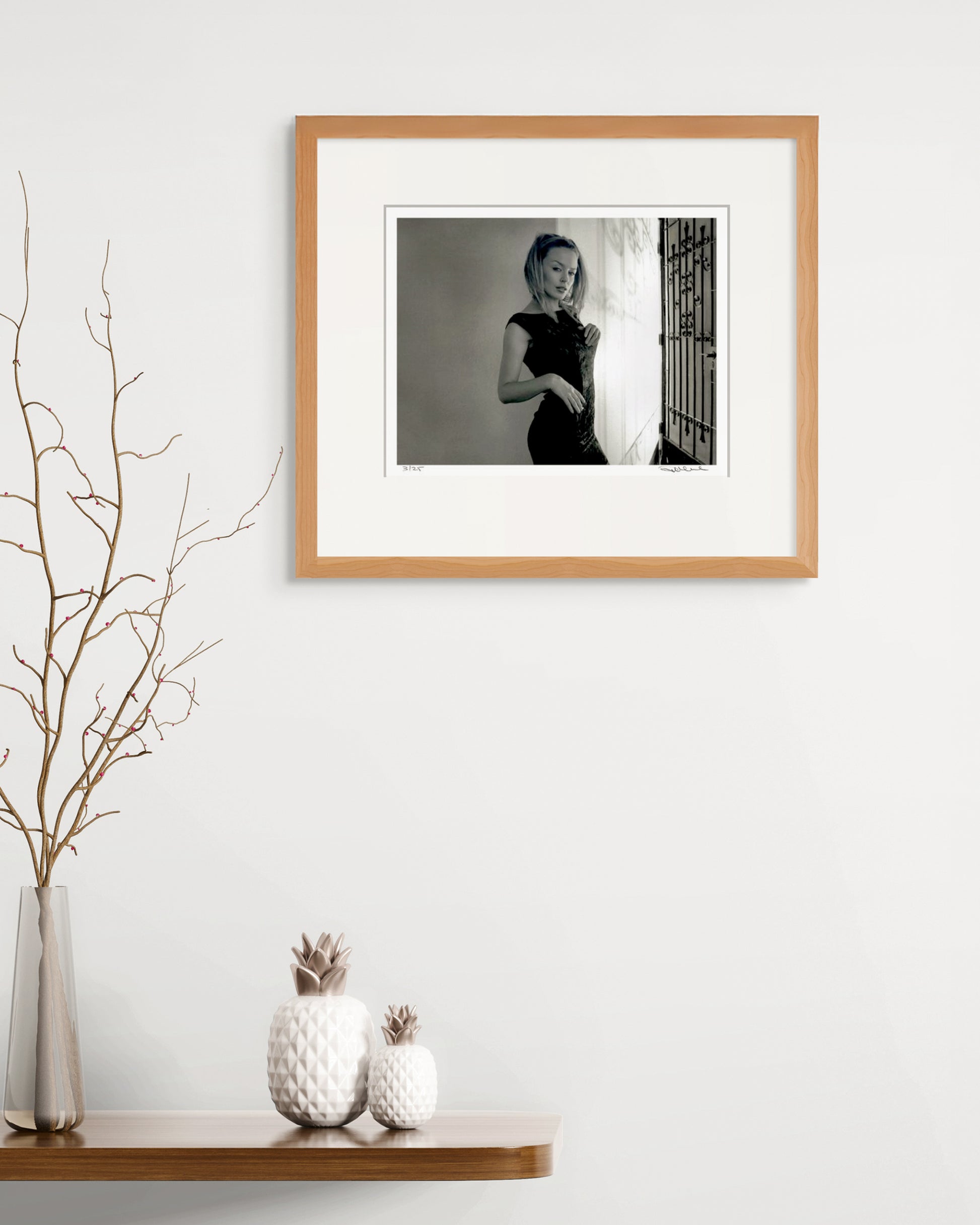 Framed Kylie Minogue portrait by Robin Sellick on a minimalist white wall with sculptural décor – refined collector display.