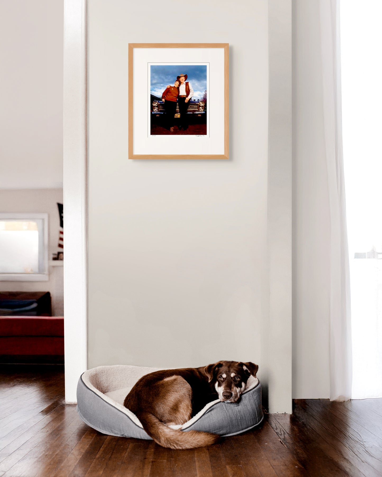 Framed Slim Dusty & Joy McKean portrait hanging above a dog resting in a warm Australian home – nostalgic, relaxed and full of country character.