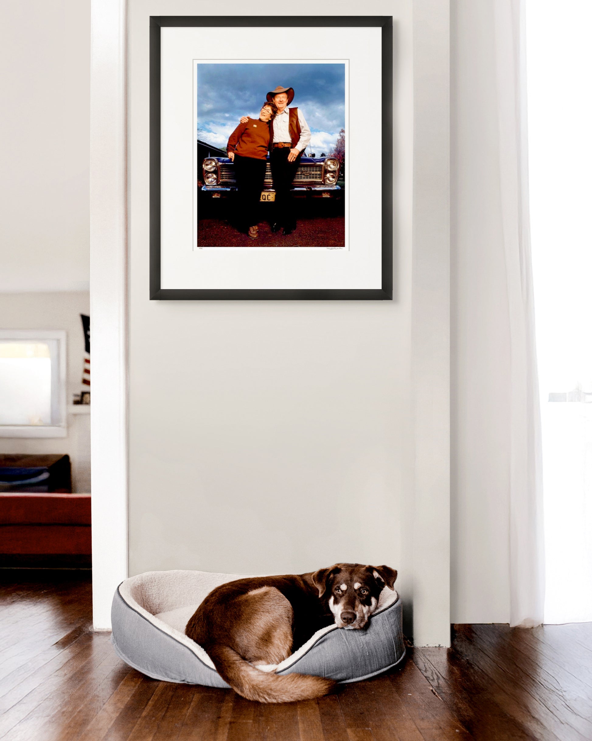 Framed limited edition photographic portrait of Slim Dusty and Joy McKean by Robin Sellick, hanging above a dog resting by a sunlit wall – a warm and familiar nod to Australian life and legacy.