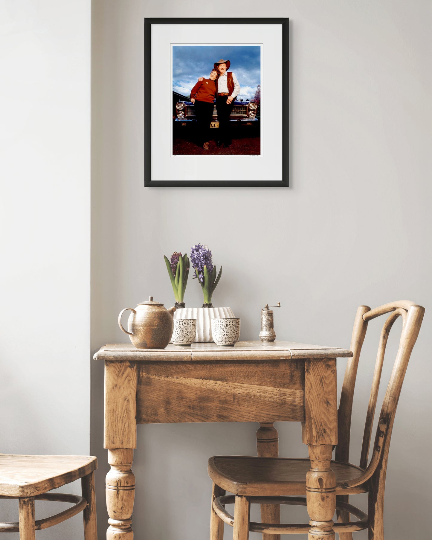 Framed portrait of Slim Dusty and Joy McKean by Robin Sellick, displayed above a rustic timber table with pottery and flowers – blending country heritage with refined Australian design.
