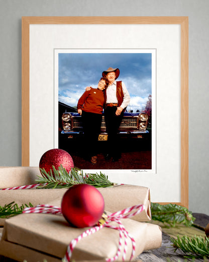 Framed limited edition Slim Dusty & Joy McKean portrait by Robin Sellick beside wrapped gifts and red Christmas ornaments – ideal collector’s gift edition.