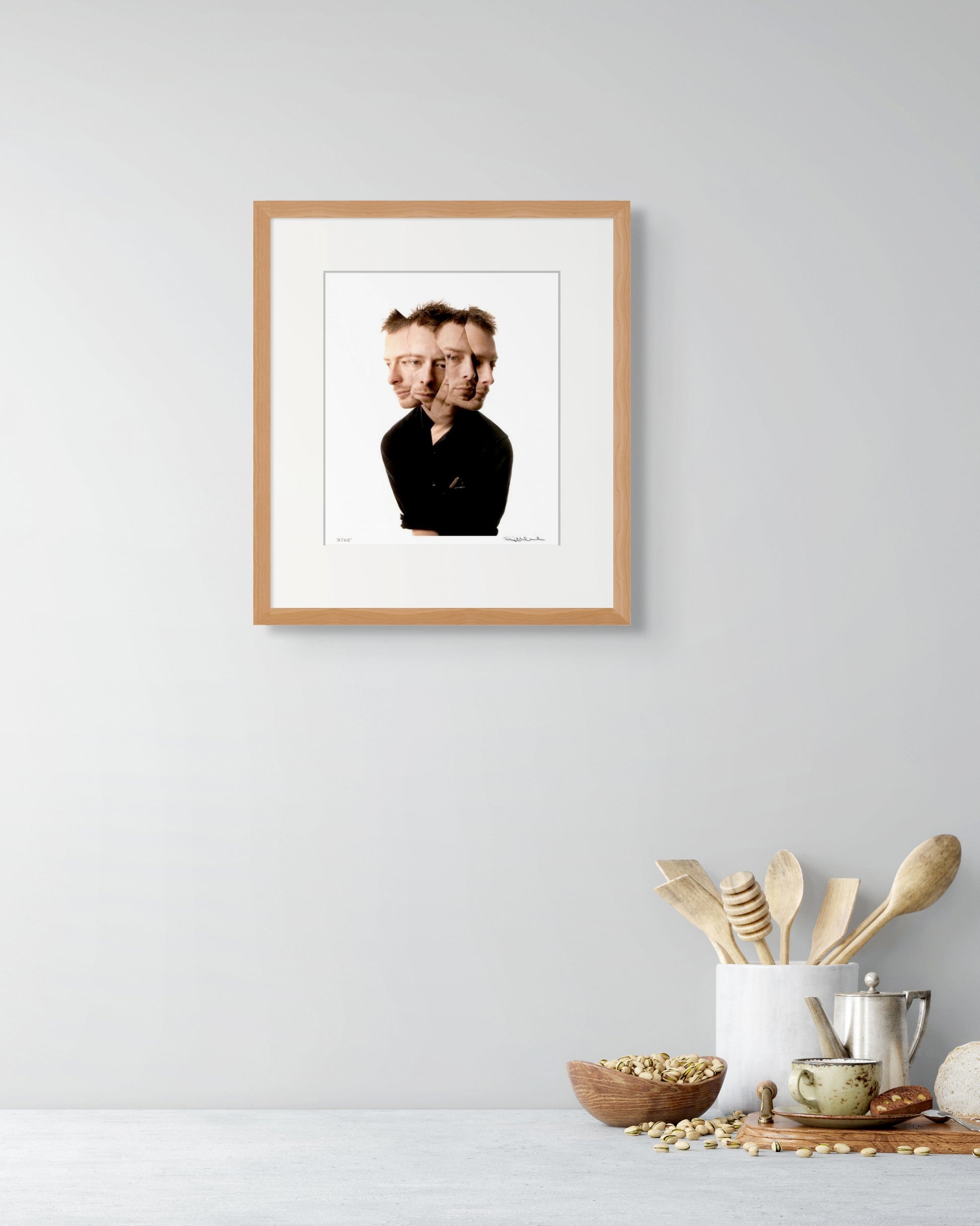 Framed Thom Yorke portrait by Robin Sellick styled in a modern kitchen with wooden utensils – art that lives comfortably in everyday spaces.
