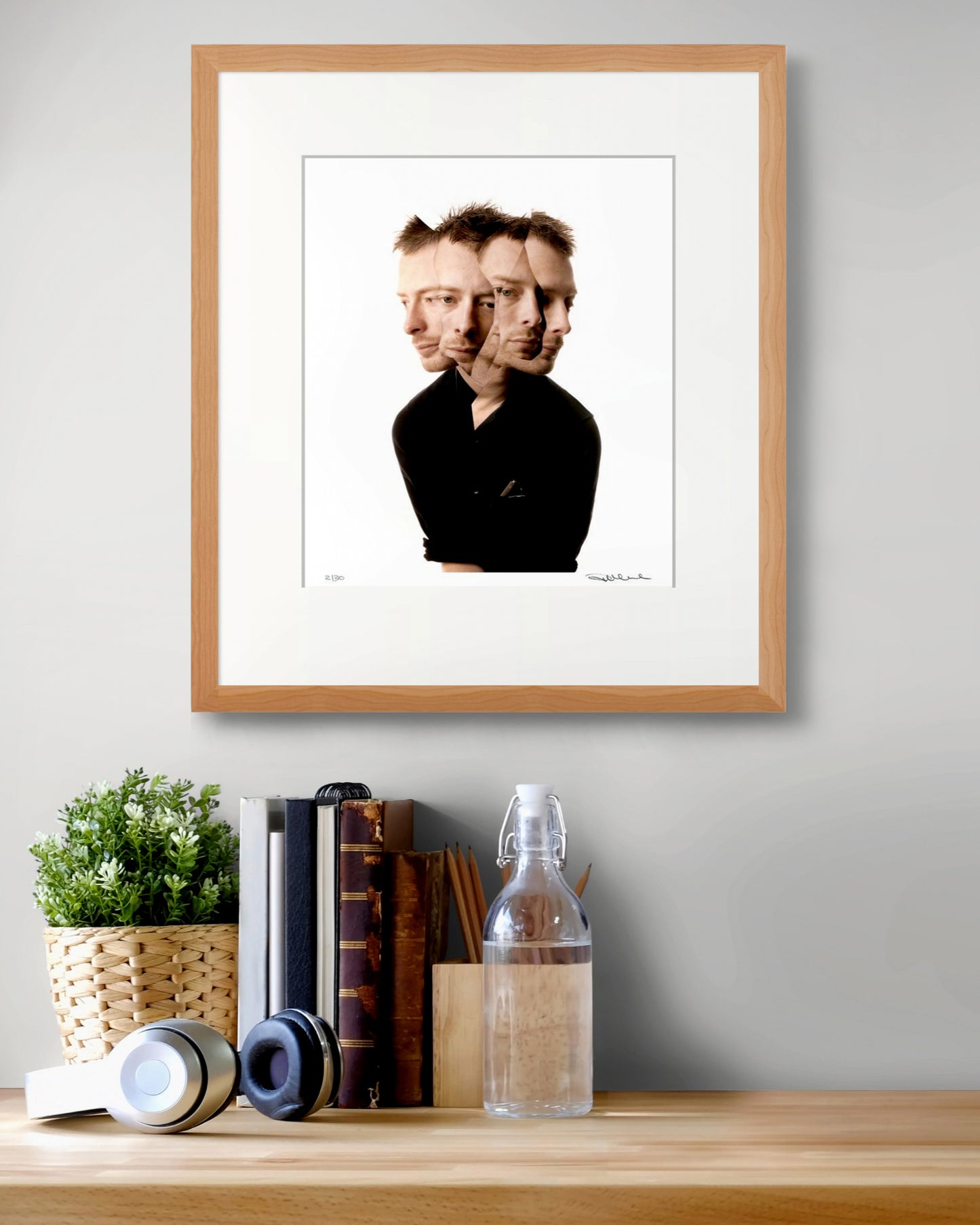 Framed limited edition Thom Yorke portrait by Robin Sellick above a desk with books, headphones and natural light – a collector’s piece from Radiohead’s OK Computer era.